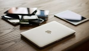 A variety of modern electronic gadgets, including a laptop and smartphones, on a wooden table.